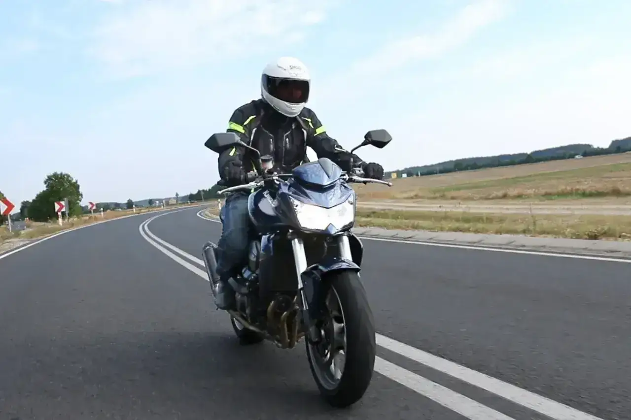 Motocyklista na Kawasaki Z750 2010 pokonuje zakręt na malowniczej drodze.
