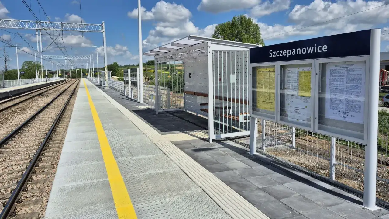 Nowa, nowoczesna linia kolejowa w Szczepanowicach z peronem, wiatą i tablicą informacyjną.
