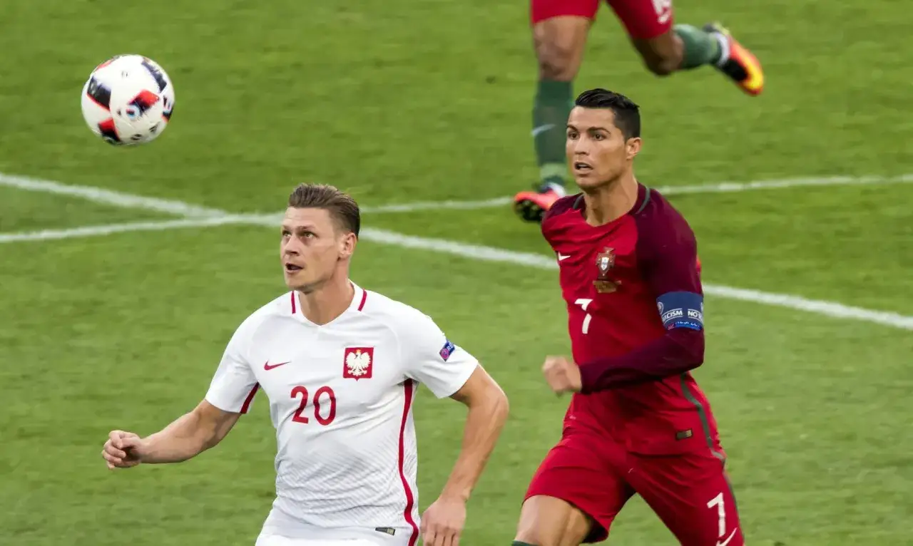 Piłkarz Polski z numerem 20 i Cristiano Ronaldo podczas meczu, fragment historii Mistrzostw Europy w Piłce Nożnej.