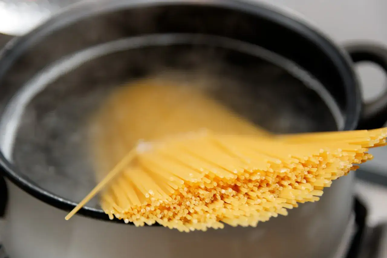 Spaghetti prêts pour la cuisson des pâtes à l'italienne dans une casserole d'eau bouillante.