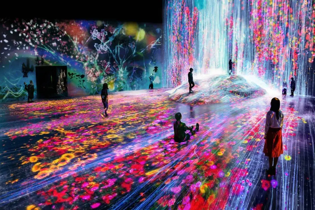 Un'installazione immersiva con cascate di fiori luminosi e un tappeto di petali colorati. Mara Oscar Cassiani ammira lo spettacolo.