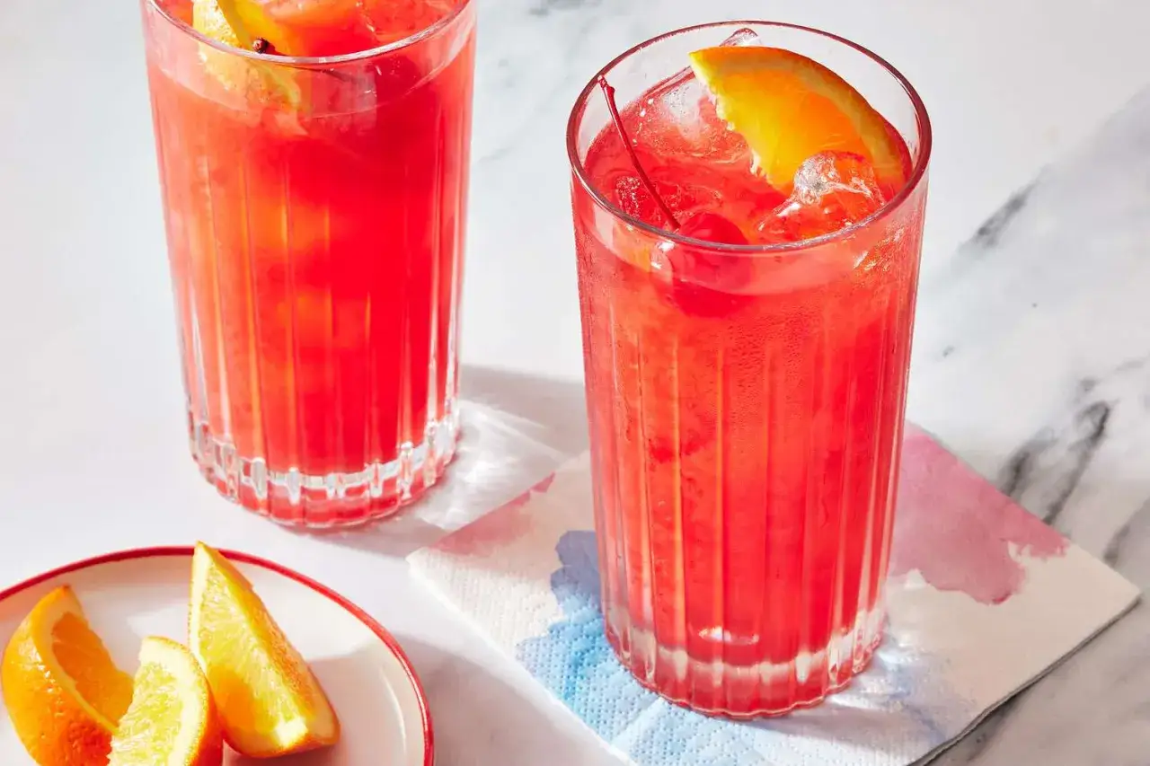 Två glas med en röd drink, garnerade med apelsinskiva och körsbär. Kanske en Alabama Slammer för att svalka sig?
