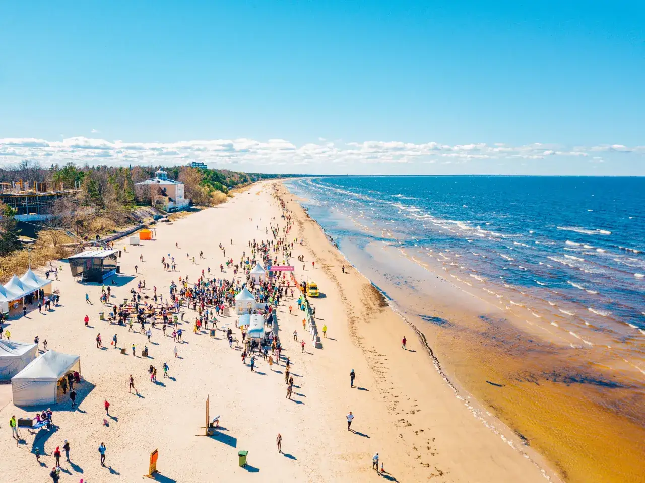 Tłum ludzi na plaży, w oddali widać morze. To dowód, że Łotwa ma dostęp do morza.