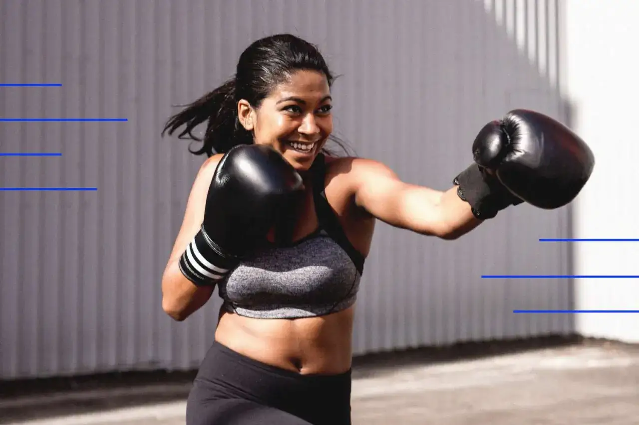 Woman in boxing gloves throws a punch, demonstrating how to increase punching power at home.