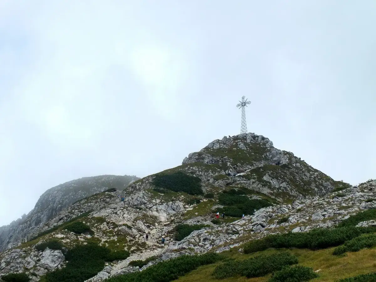 Szczyt Giewontu z krzyżem, na który wspinają się turyści. Wysokość Giewontu to 1894 m.