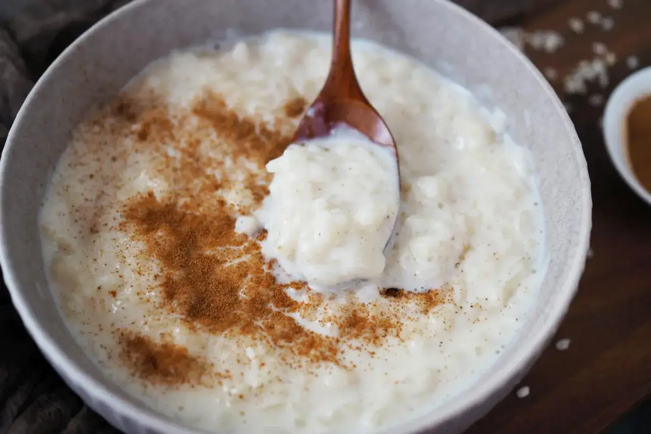 Cremiger Milchreis mit Zimt, perfekt für ein einfaches Milchreis Rezept. Eine Löffelprobe zeigt die köstliche Konsistenz.