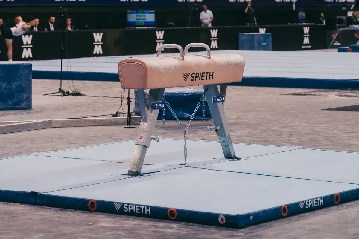 Le cheval de gymnastique, prêt pour l'action. Un athlète s'élance en arrière-plan.