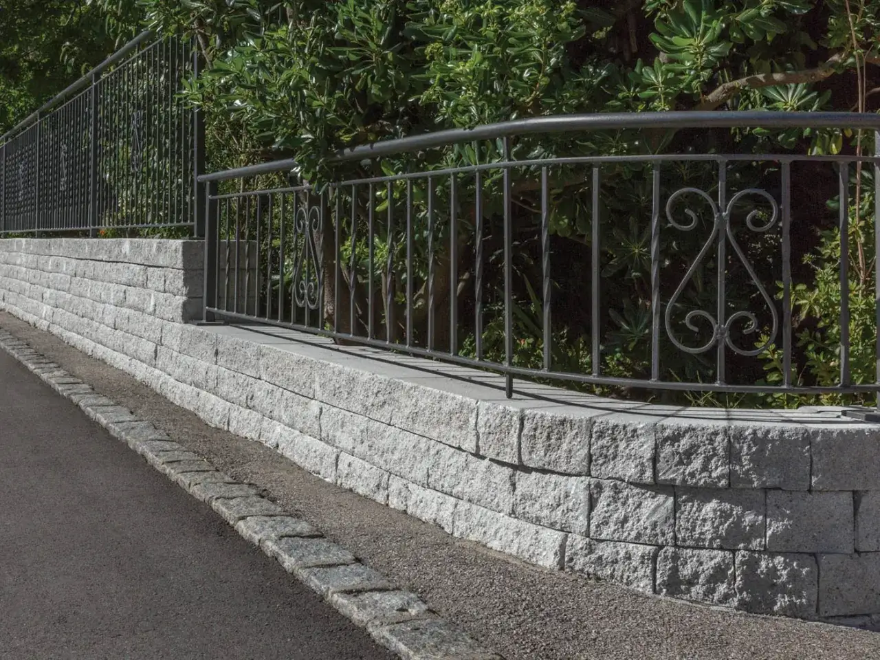 Muro in pietra grigia con ringhiera in ferro battuto, un'idea per muri di recinzione eleganti e moderni.