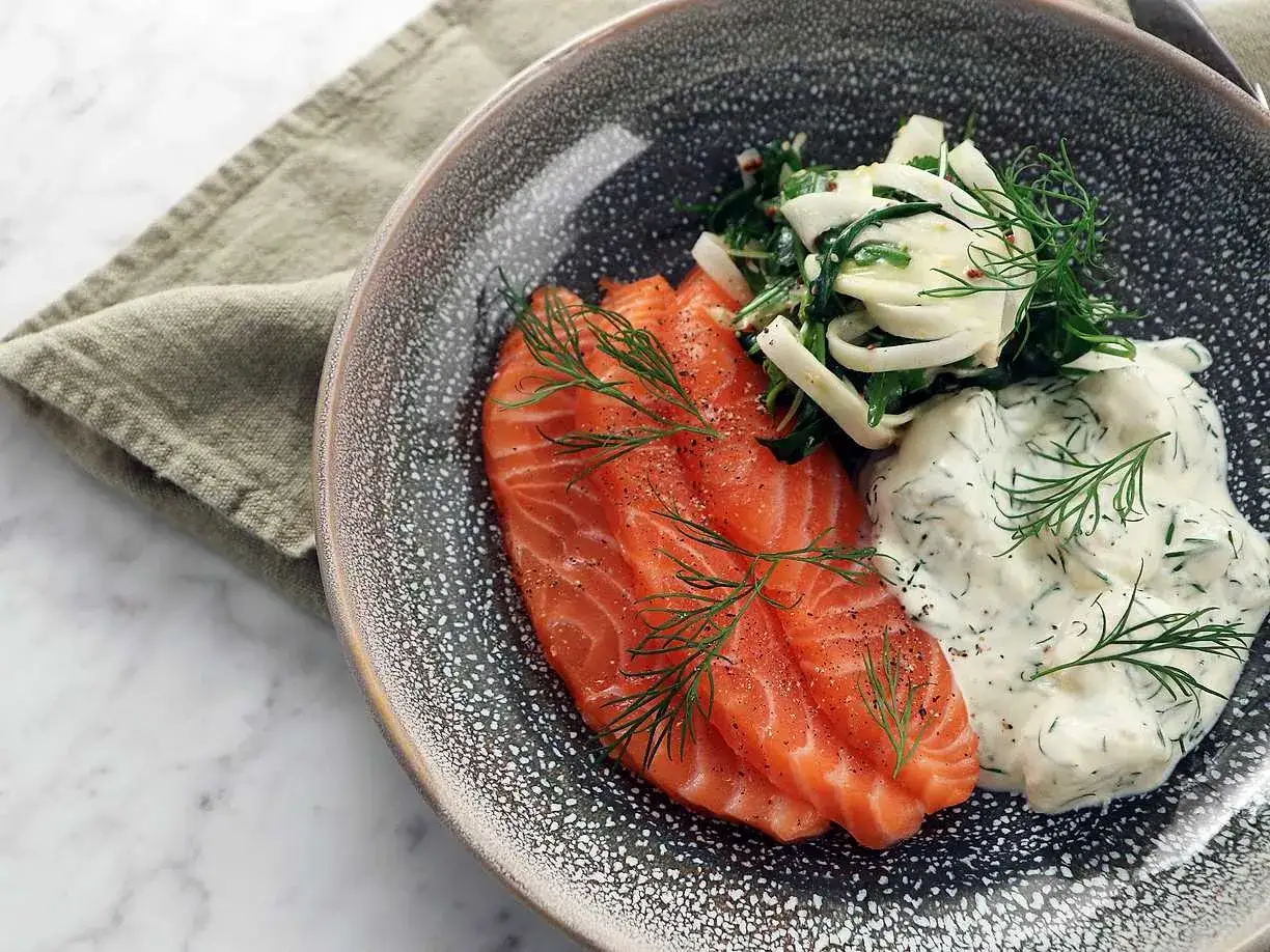 V&auml;lsmakande rimmad lax med dill och en fr&auml;sch f&auml;nk&aring;lssallad, serverad med en kr&auml;mig s&aring;s.