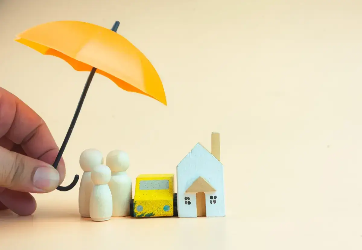 Une main protège une famille, une voiture et une maison sous un parapluie jaune, symbolisant la pérennité de leur bien-être.