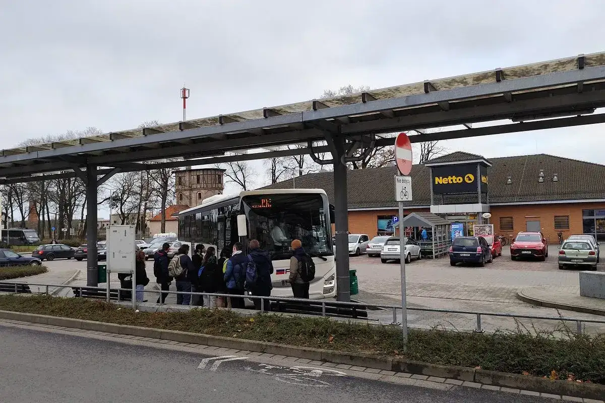 Ludzie czekają na autobus na przystanku w Poznaniu Mielnie, obok sklepu Netto.