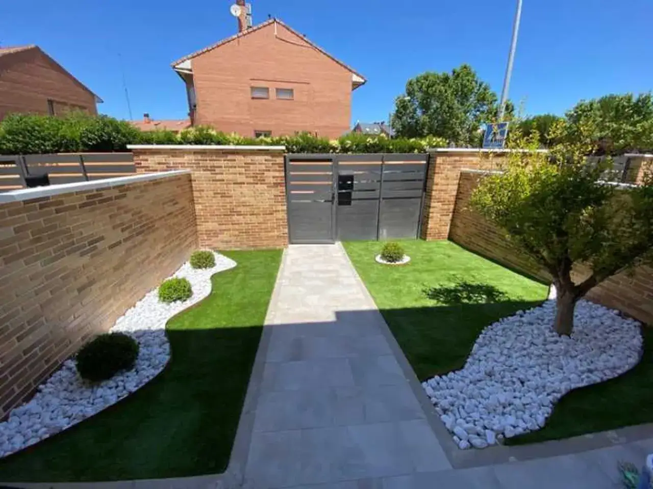 Jardines modernos con césped artificial y piedras blancas, creando un diseño limpio y minimalista.