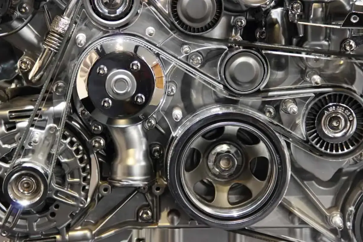 Gros plan sur un moteur chromé, avec la courroie de distribution tendue entre les poulies, prête à synchroniser le mouvement.