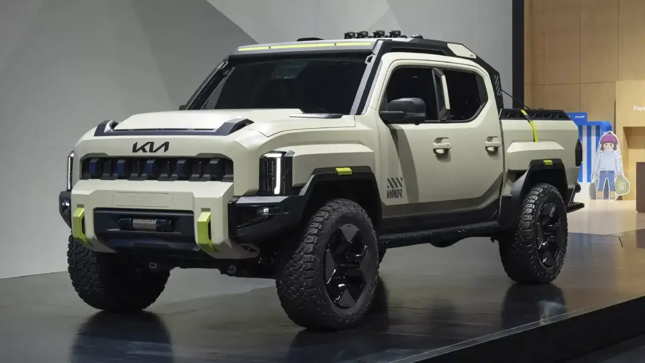Nowy, masywny pickup Kia Tasman w kolorze piaskowym, z żółtymi akcentami i terenowymi oponami, gotowy na przygodę.