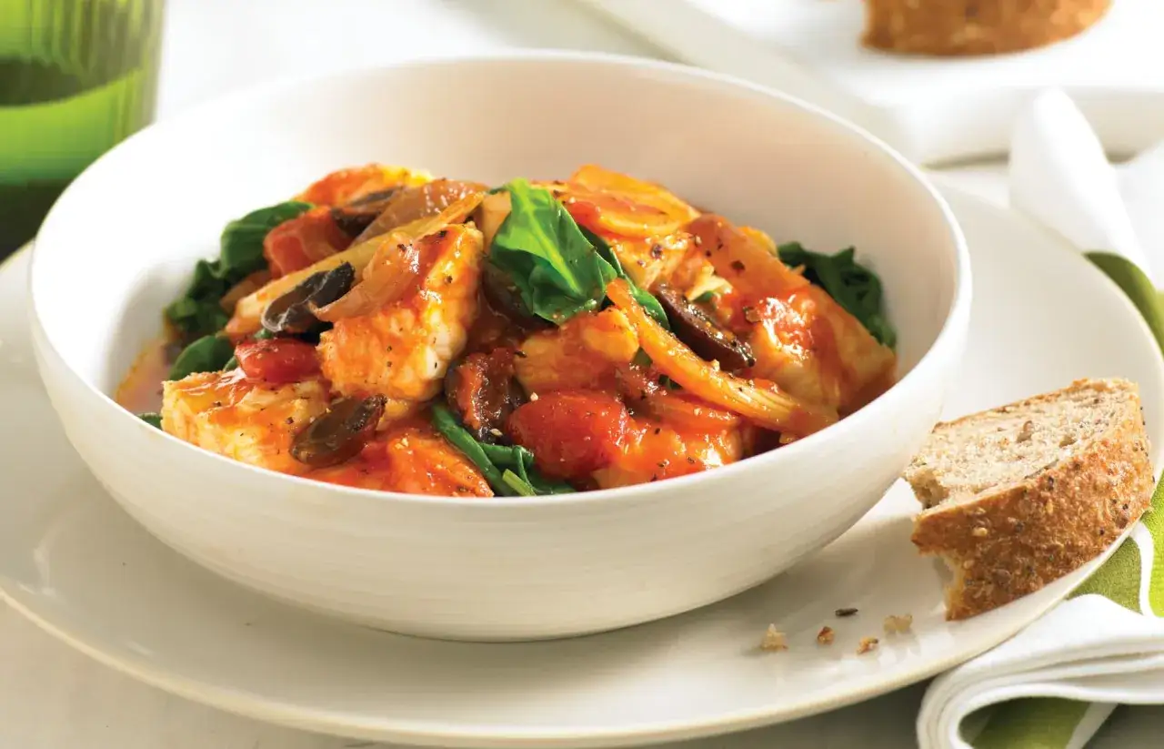 Herzhafter Fenchel-Fisch-Eintopf in Tomatensauce mit Spinat und Brot.