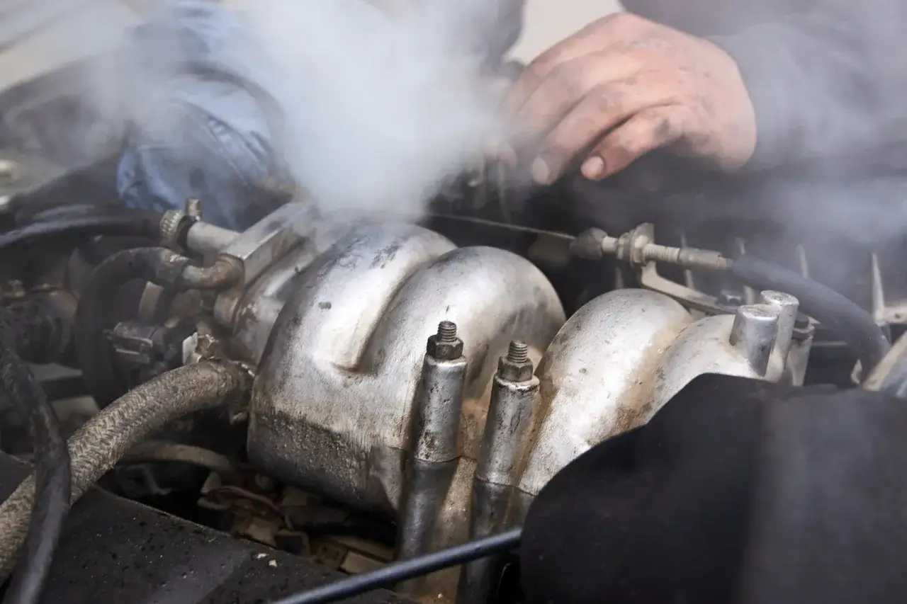 Fumo bianco dal motore, un meccanico con le mani sporche cerca di capire il problema.