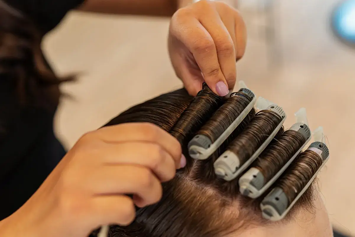 H&aring;rstylist s&auml;tter i spolar f&ouml;r permanent. Undrar du hur l&aring;ng tid tar det att permanenta h&aring;ret?
