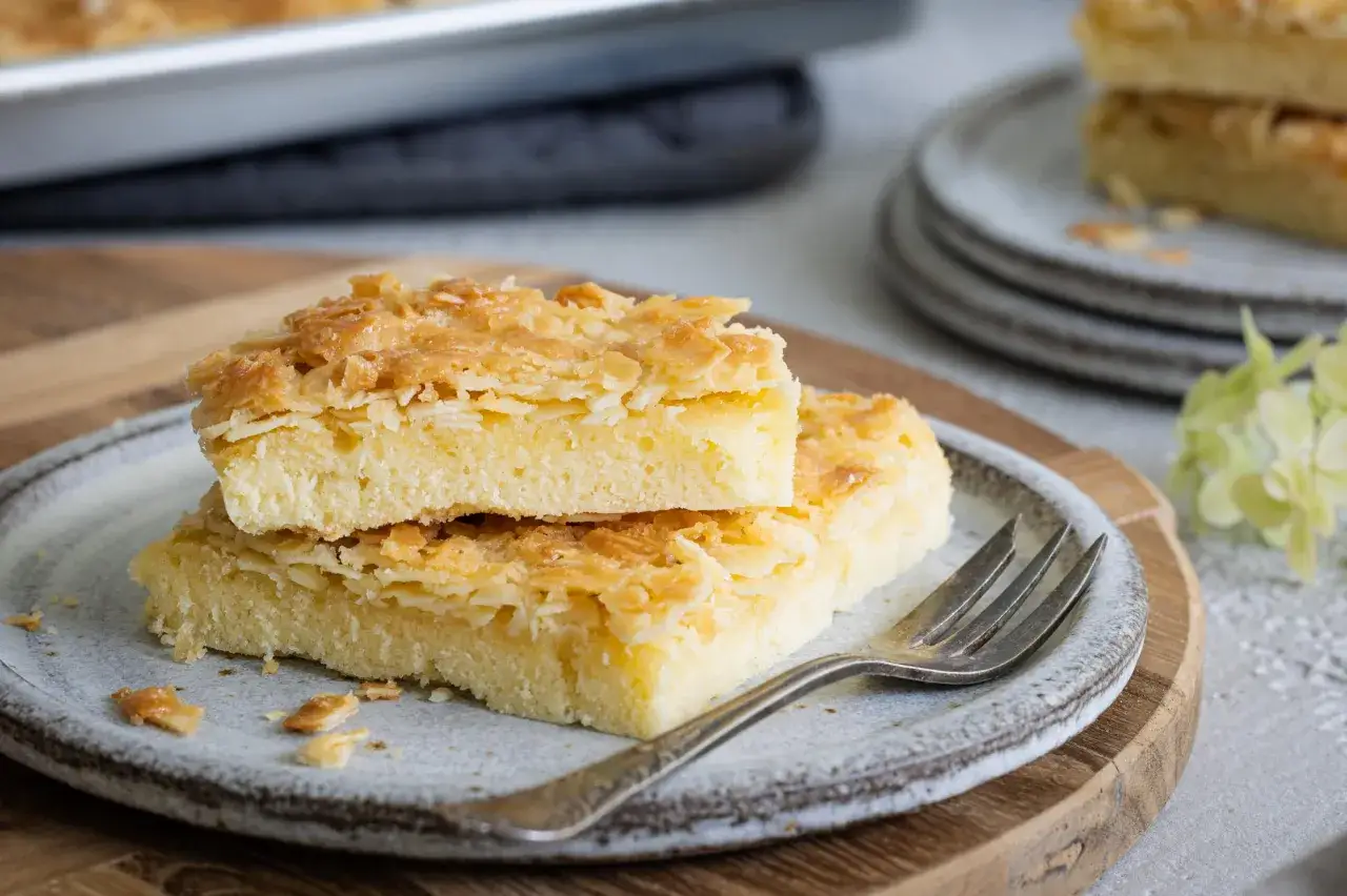 Zwei St&uuml;cke saftiger Butterkuchen ohne Hefe, belegt mit knusprigen Mandelbl&auml;ttchen, liegen auf einem Teller.