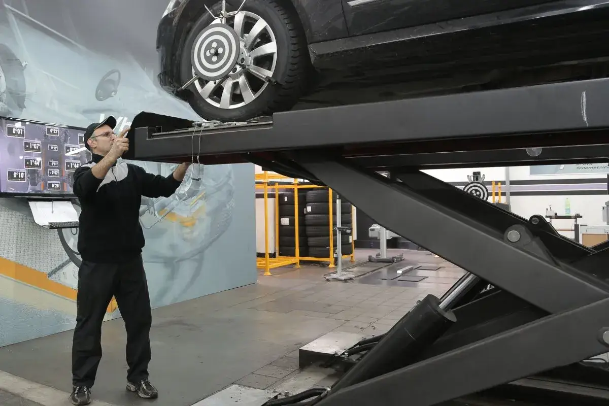 Mechanik ustawia czujniki do pomiaru geometrii kół. Na ekranie widać dane kątów pochylenia.