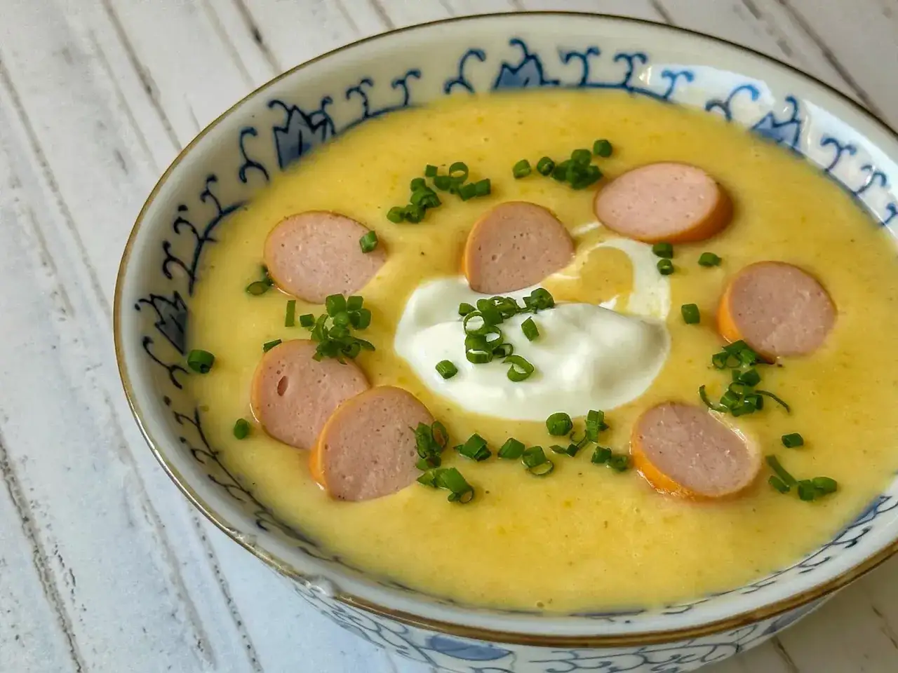 Cremige Kartoffelsuppe mit Wurstscheiben, einem Klecks Sauerrahm und Schnittlauch. Ein einfaches Gericht aus unseren Suppen Rezepten.