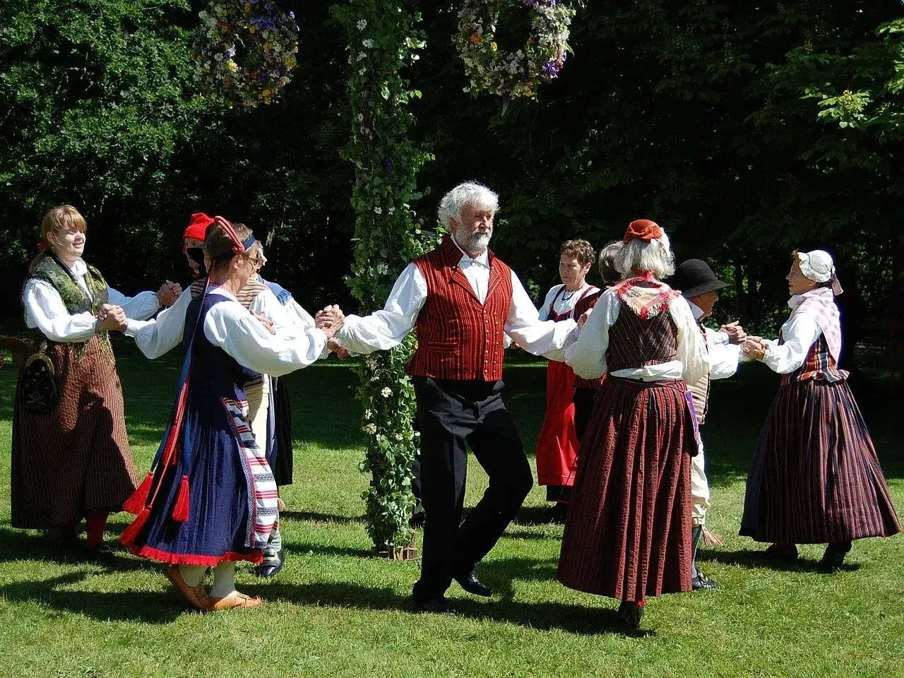 Un gruppo di persone in abiti tradizionali danza in cerchio, celebrando il folclore.