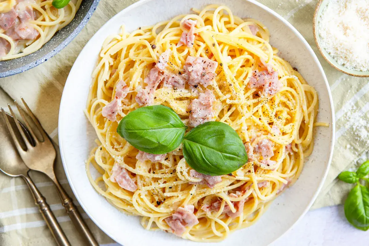 Eine cremige Carbonara mit Spaghetti, Speckwürfeln und frischem Basilikum. Perfekt für ein schnelles Abendessen.