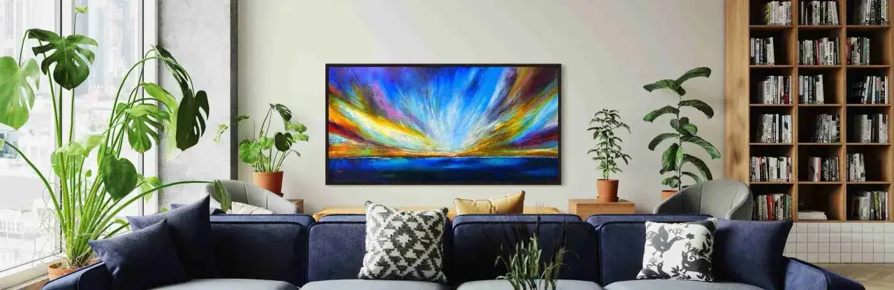 A vibrant abstract painting of a sunset over the ocean hangs above a navy sofa, offering inspiration on how to choose art for your home.