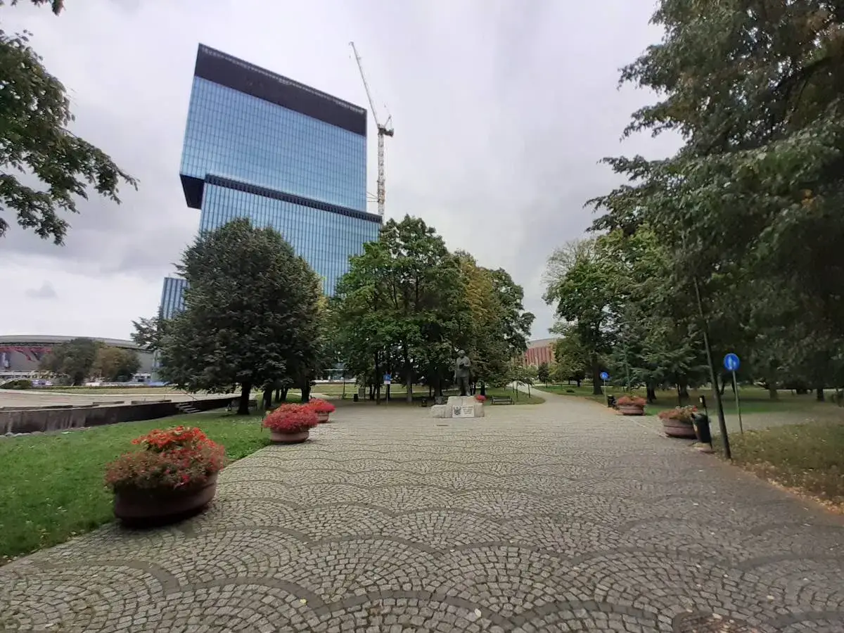 Nowoczesny wieżowiec i park z pomnikiem. Jedna z wielu katowickich atrakcji, idealne miejsce na spacer.