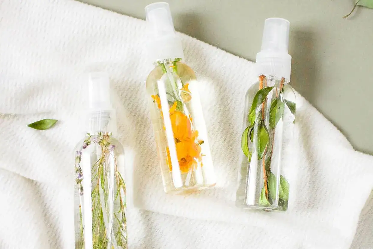 Drei Spr&uuml;hflaschen mit Kr&auml;utern und Bl&uuml;ten, perfekt zum erfrischungsspray selber machen.