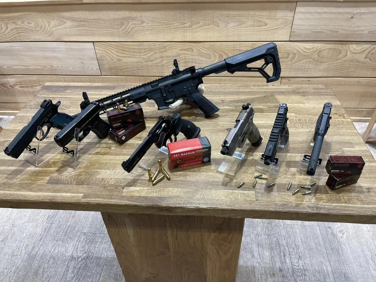 Plusieurs armes, dont un fusil d'assaut et des pistolets, sont présentées avec des boîtes de munitions. Idéal pour le tir sportif avec licence.