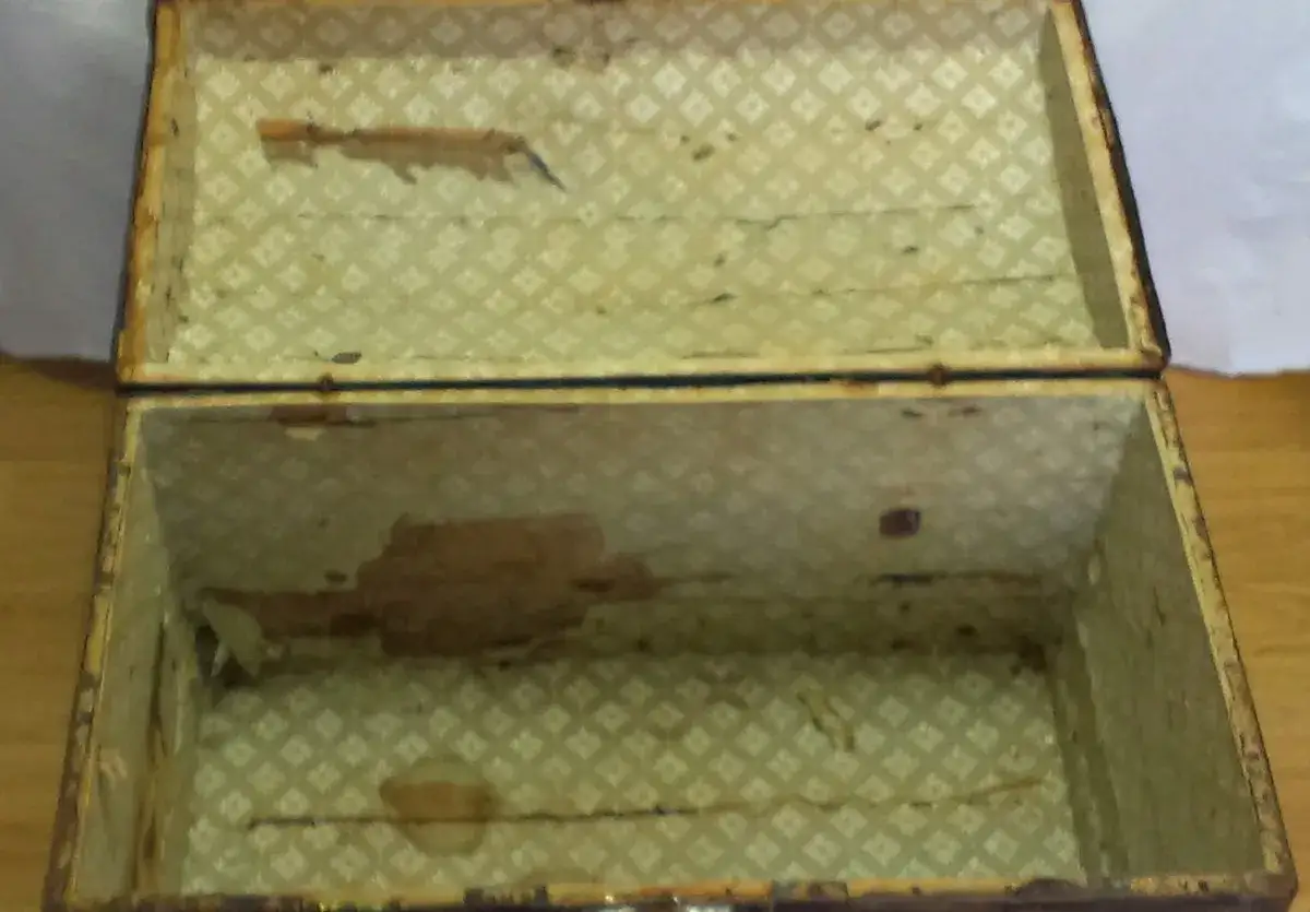 Interior de ba&uacute;l antiguo con forro de rombos verdes. Se aprecia la chapa para restaurar el ba&uacute;l, con detalles en lat&oacute;n.