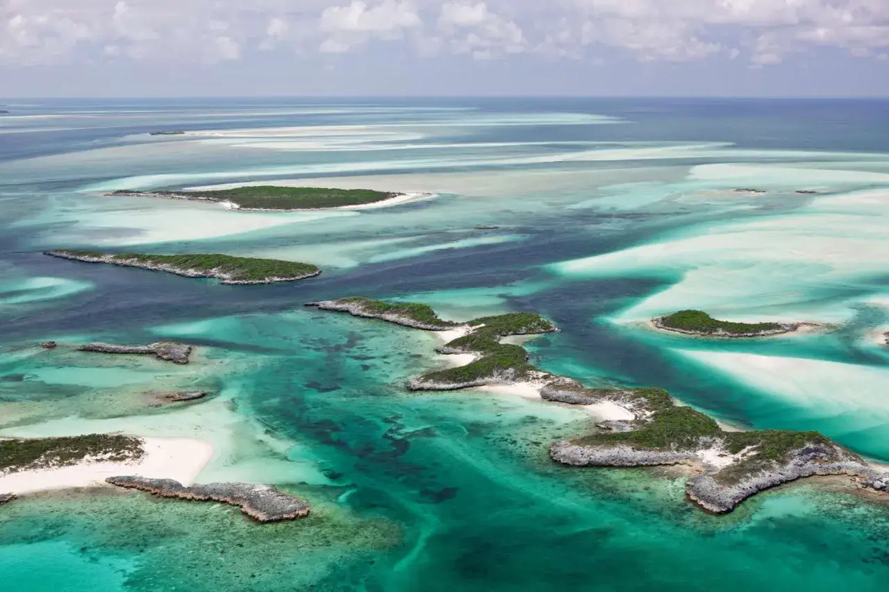 Vue aérienne des Bahamas, un archipel de petites îles verdoyantes bordées de plages de sable blanc et d'eaux turquoise. Idéal pour savoir que faire aux Bahamas.
