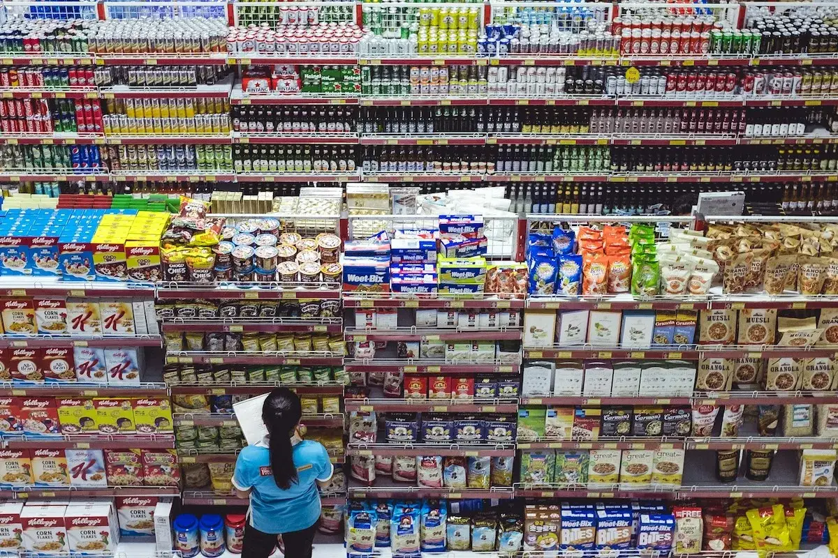 Ein Mitarbeiter sortiert Produkte in einem Asia Markt Berlin. Regale voller Getr&auml;nke, M&uuml;sli und Snacks.