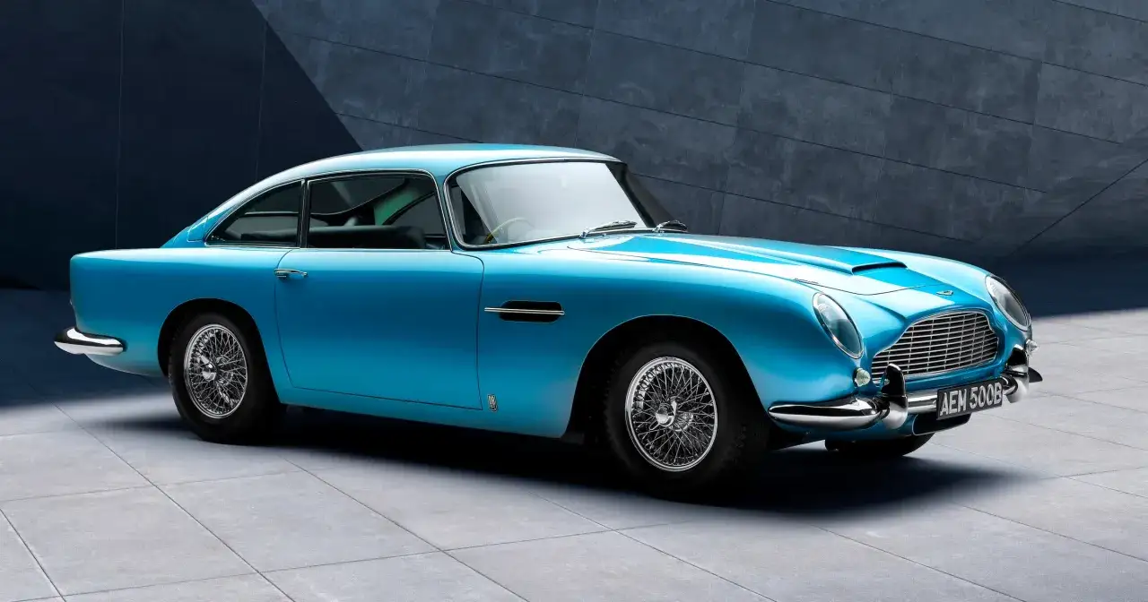 Błękitny Aston Martin DB5 z charakterystycznymi szprychowymi felgami, lśniącym chromem i kultową kratką chłodnicy.