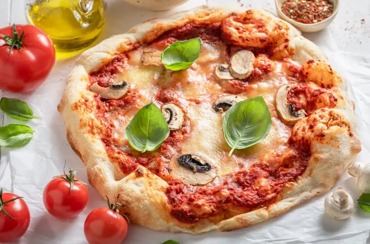 Pyszna pizza wegańska z pieczarkami, pomidorami i bazylią. Składniki tej pysznej pizzy wyglądają apetycznie.