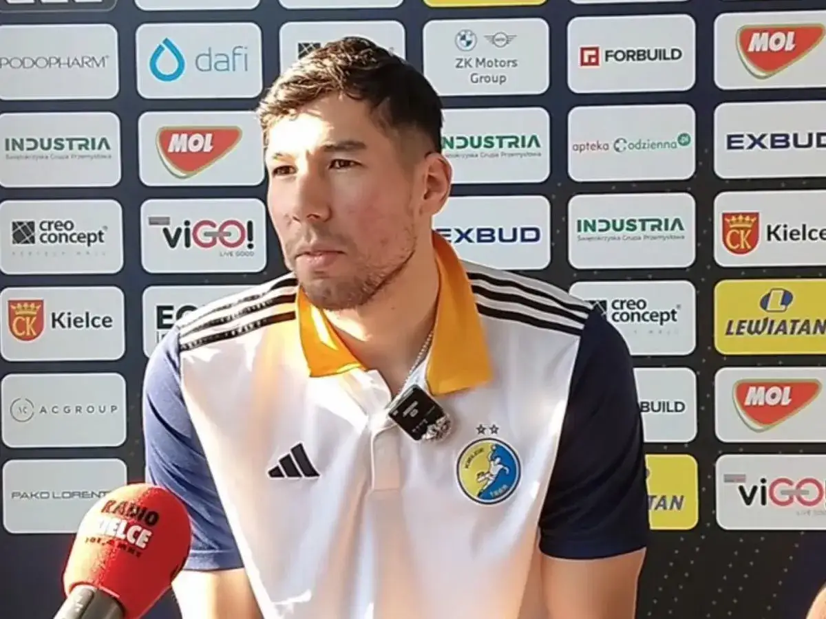 Daniel Dujshebaev w koszulce z herbem klubu, przed ścianką sponsorską z logo "Industria Kielce".