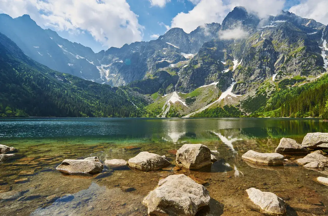 Kamienista droga na Morskie Oko prowadzi przez malownicze Tatry. Jezioro odbija skaliste szczyty i zielone lasy.