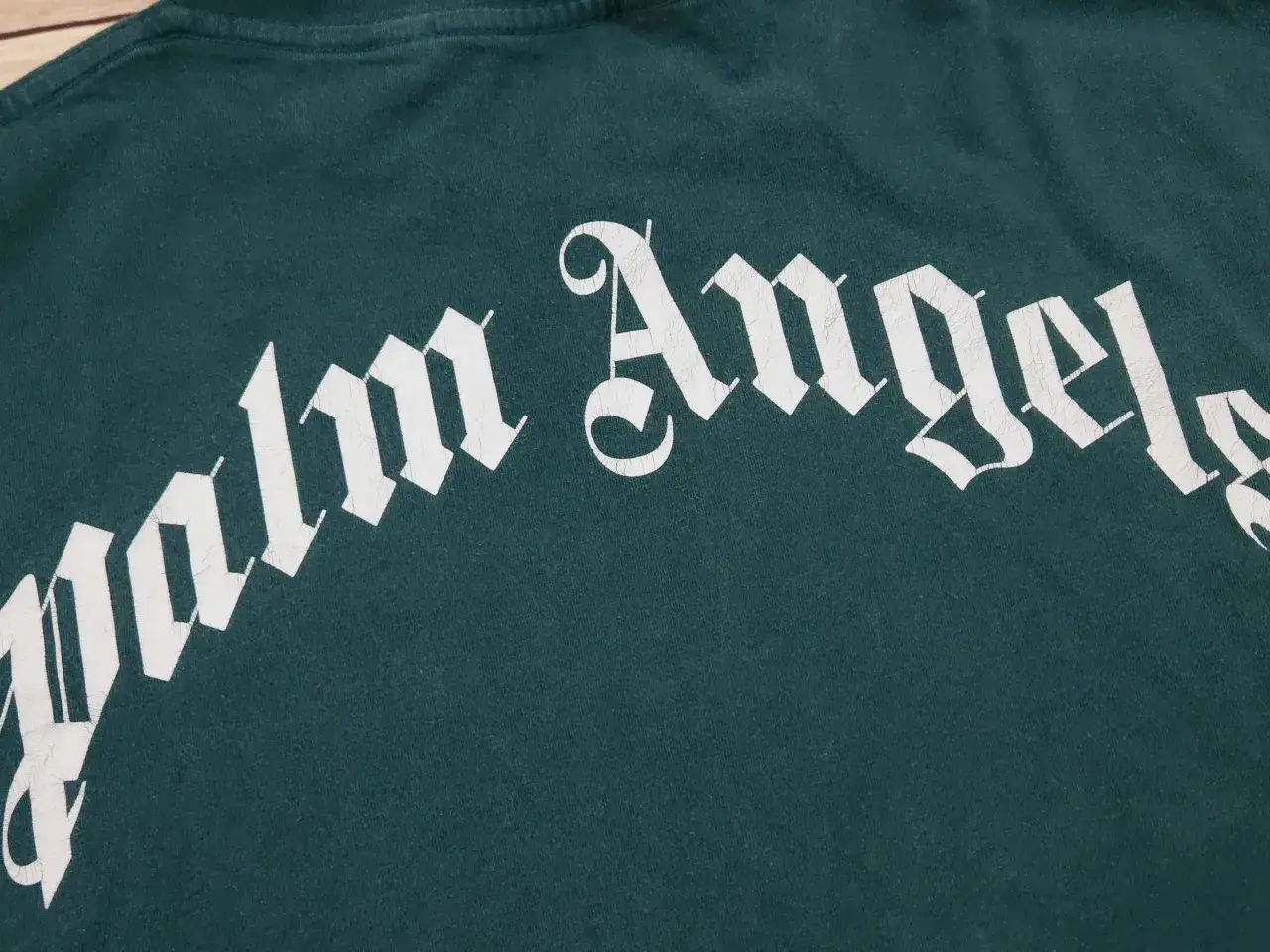 Zielona koszulka Palm Angels z białym, stylizowanym napisem.