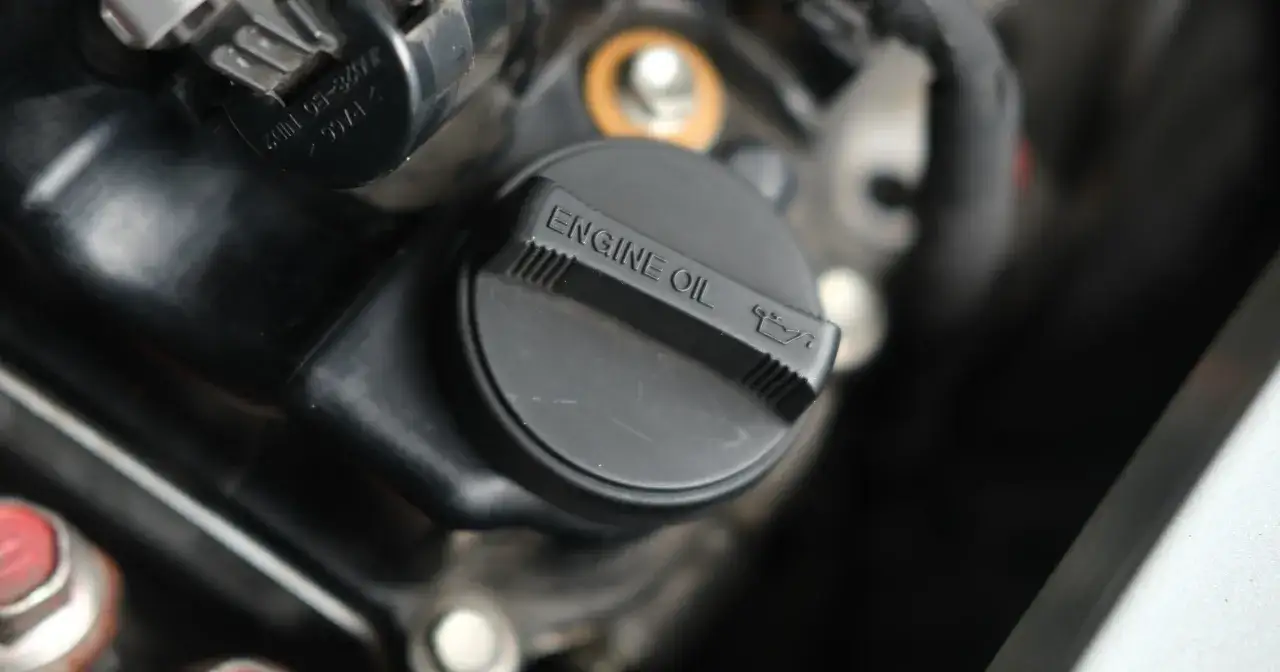 Czarny korek wlewu oleju silnikowego z napisem "ENGINE OIL" i ikonką. Pamiętaj o regularnej wymianie oleju, by silnik działał sprawnie.