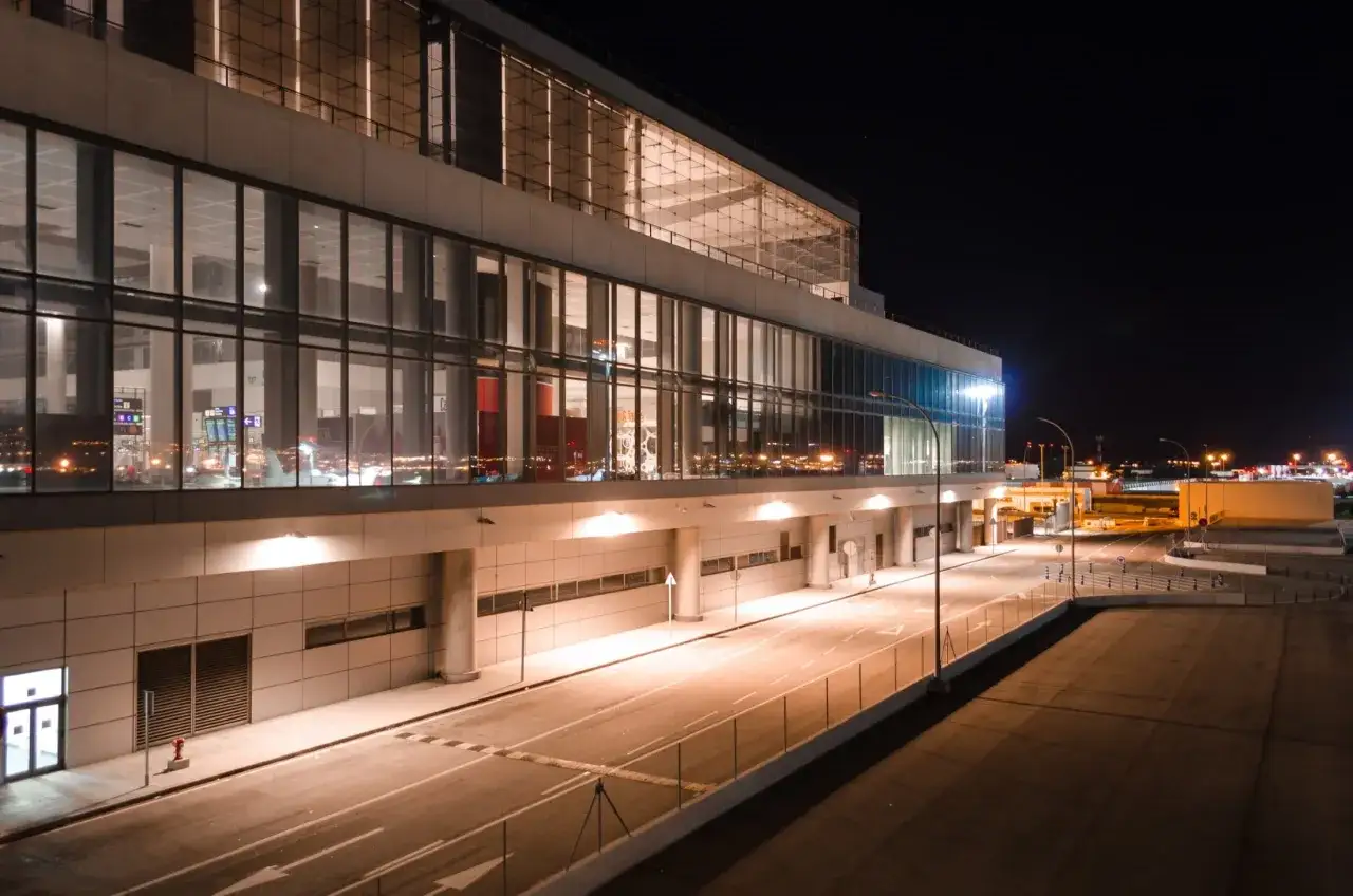 Nowoczesny terminal lotniska w nocy, z oświetlonymi oknami i pustymi drogami. Wygląda jak marbella lotnisko.