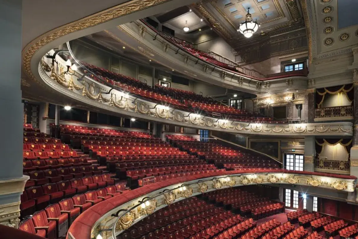 Eleganckie wnętrze teatru z czerwonymi fotelami i złotymi zdobieniami. Idealne miejsce, by sprawdzić, na co warto iść do teatru w Warszawie.