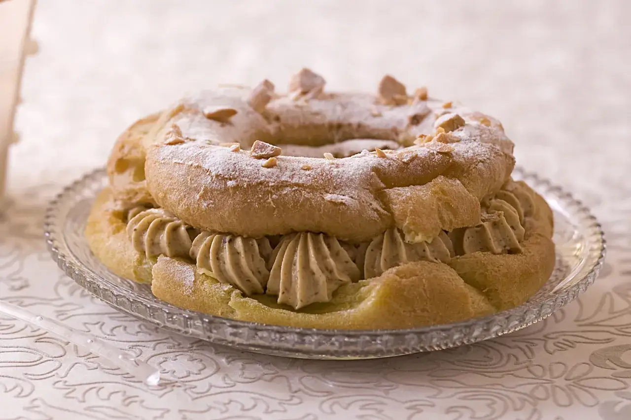 Un Paris-Brest, plat typique d'Île-de-France, garni de crème onctueuse et saupoudré de sucre glace et d'amandes.
