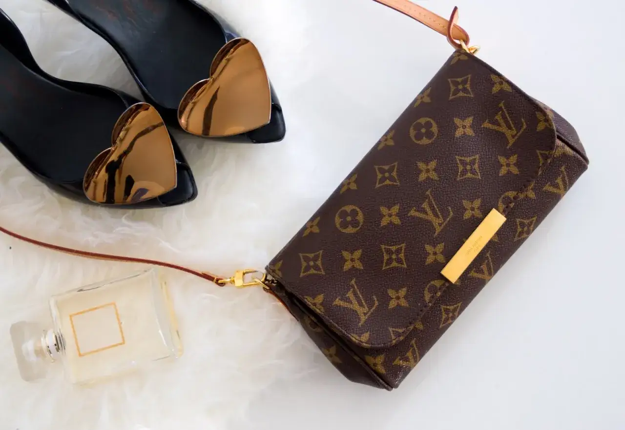 Torebka Louis Vuitton, czarne buty z sercami, perfumy na białym tle.