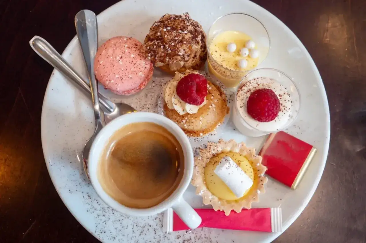 Assortiment de spécialités culinaires parisiennes : macarons, éclairs, tartellettes, verrines et café. Un délice pour les yeux et les papilles.