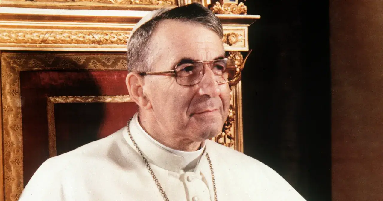Papież Jan Paweł I, który był papieżem przed Janem Pawłem II, w białej sutannie i okularach.