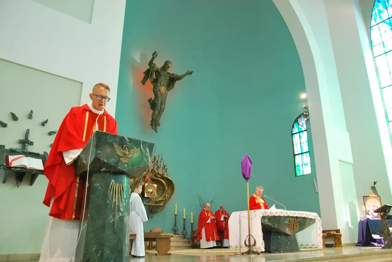 Nabożeństwo w kościele. Ksiądz w czerwonej szacie przy pulpicie, obok ministrant. W tle figura Jezusa i obraz. To może być tekst o męce pańskiej.