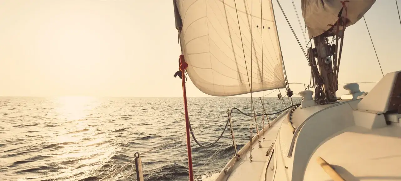 Segelboot gleitet über ruhige See im Sonnenuntergang. Die Segel sind straff gespannt, bereit für die nächste Etappe. Ein Moment der Ruhe vor dem **ausbessern der Segel** für die nächste Reise.