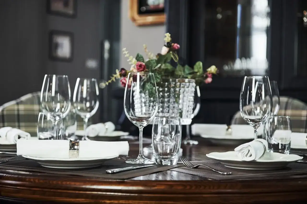 Une table dressée pour un repas, avec des verres à eau à droite et à gauche des assiettes.