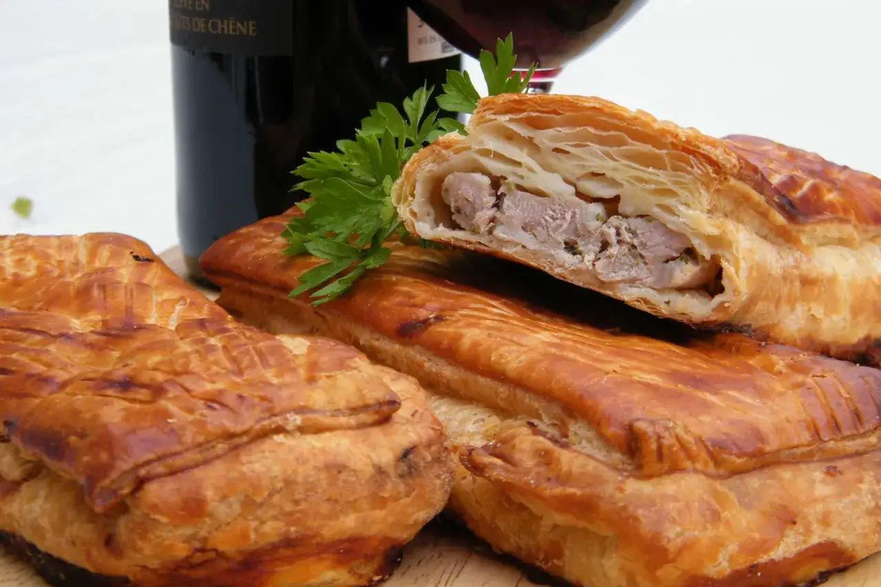 Pâté en croûte, une spécialité lorraine savoureuse, garni de viande et d'herbes, prêt à être dégusté avec un verre de vin.