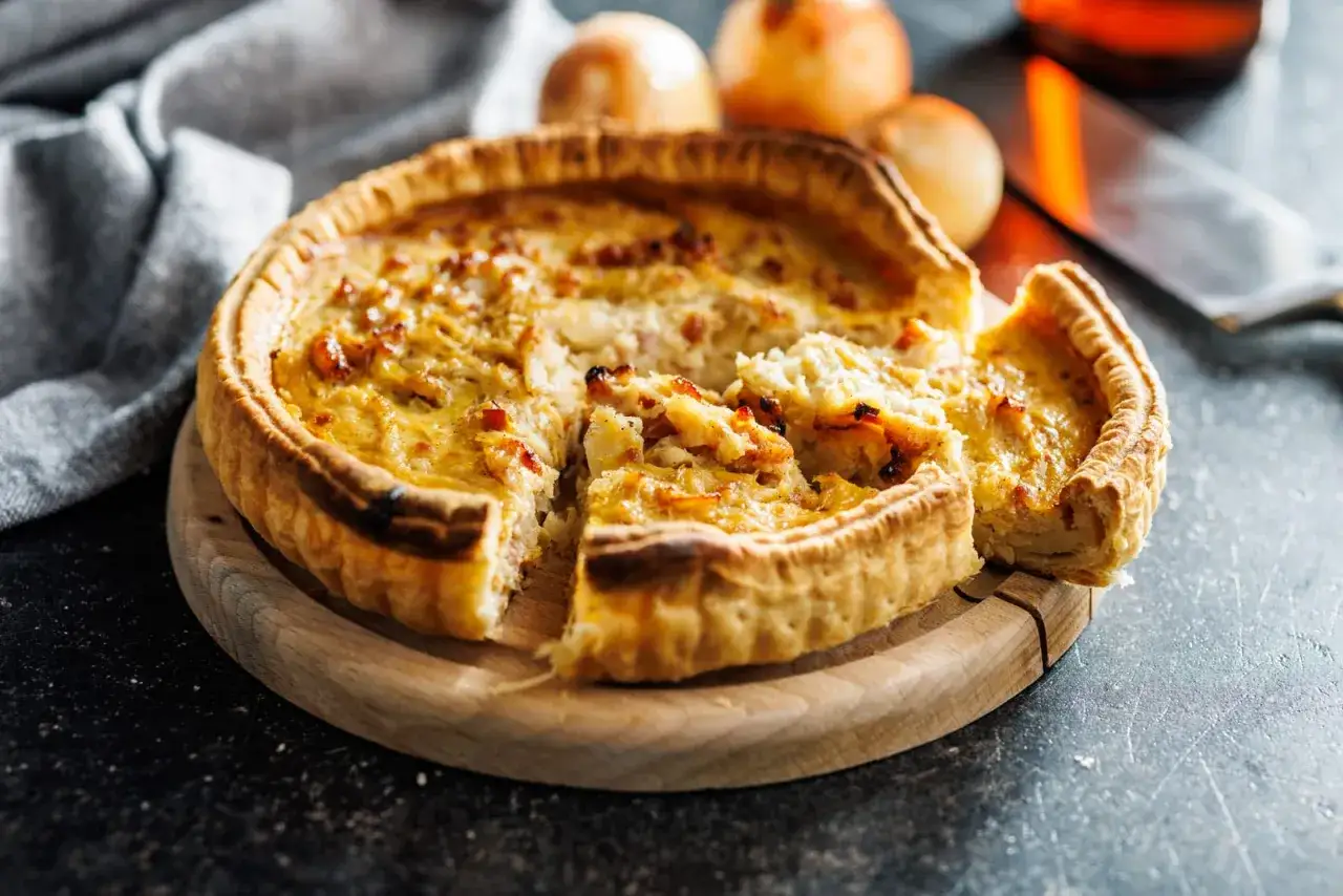 Une part de quiche lorraine, une des spécialités lorraines, sur une planche en bois.